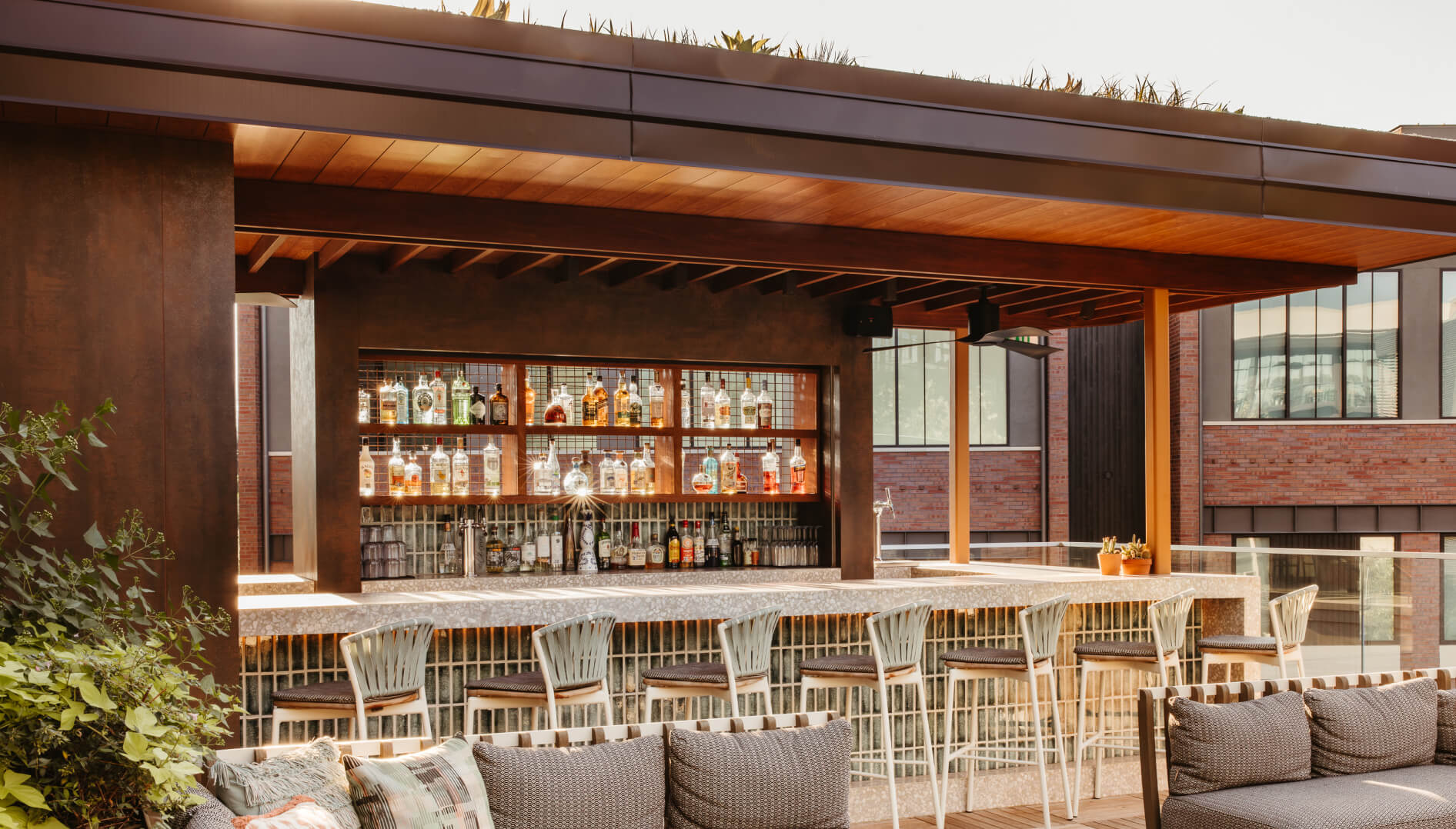 Modern outdoor bar featuring a lush living roof, sleek barstools on three sides, and contemporary lounge seating near the pool deck.