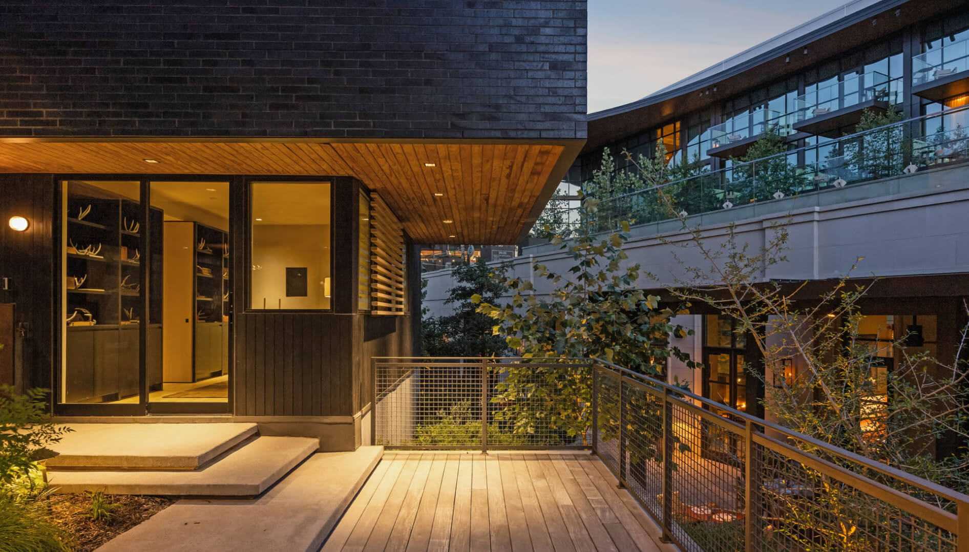 Evening view from Unit 6’s outdoor deck at The Seven, highlighting the office interior and adjacent Bowie House balconies and deck area.