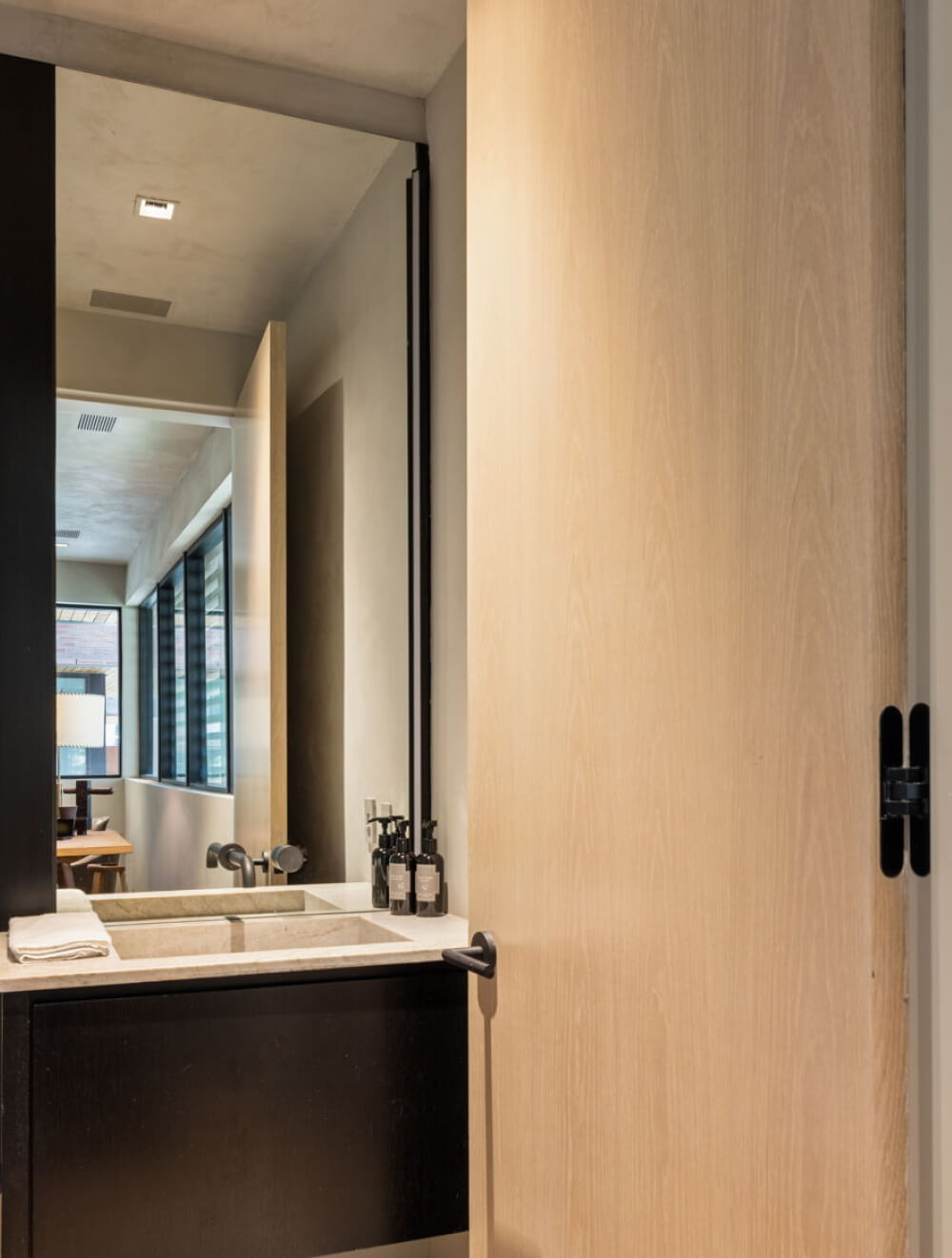 View into the powder room from the hallway, with the door open revealing curated interior finishes.