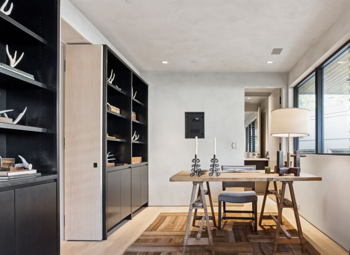 Custom built-in shelving and a minimalist desk paired with a modern chair, styled within the versatile flex space of Unit 6.