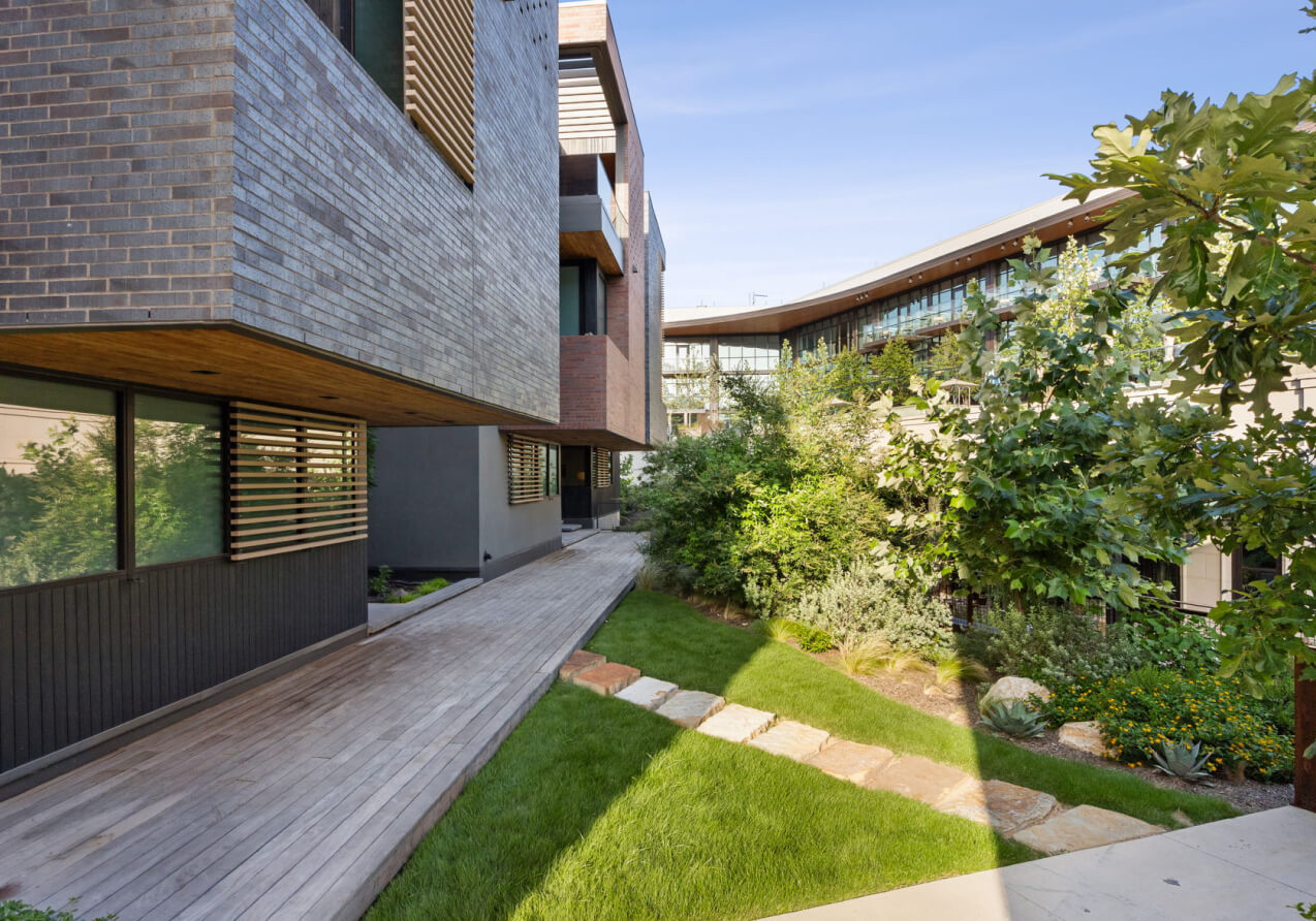 Modern decking and stone pathways winding through lush landscaping between The Seven residences and the hotel.