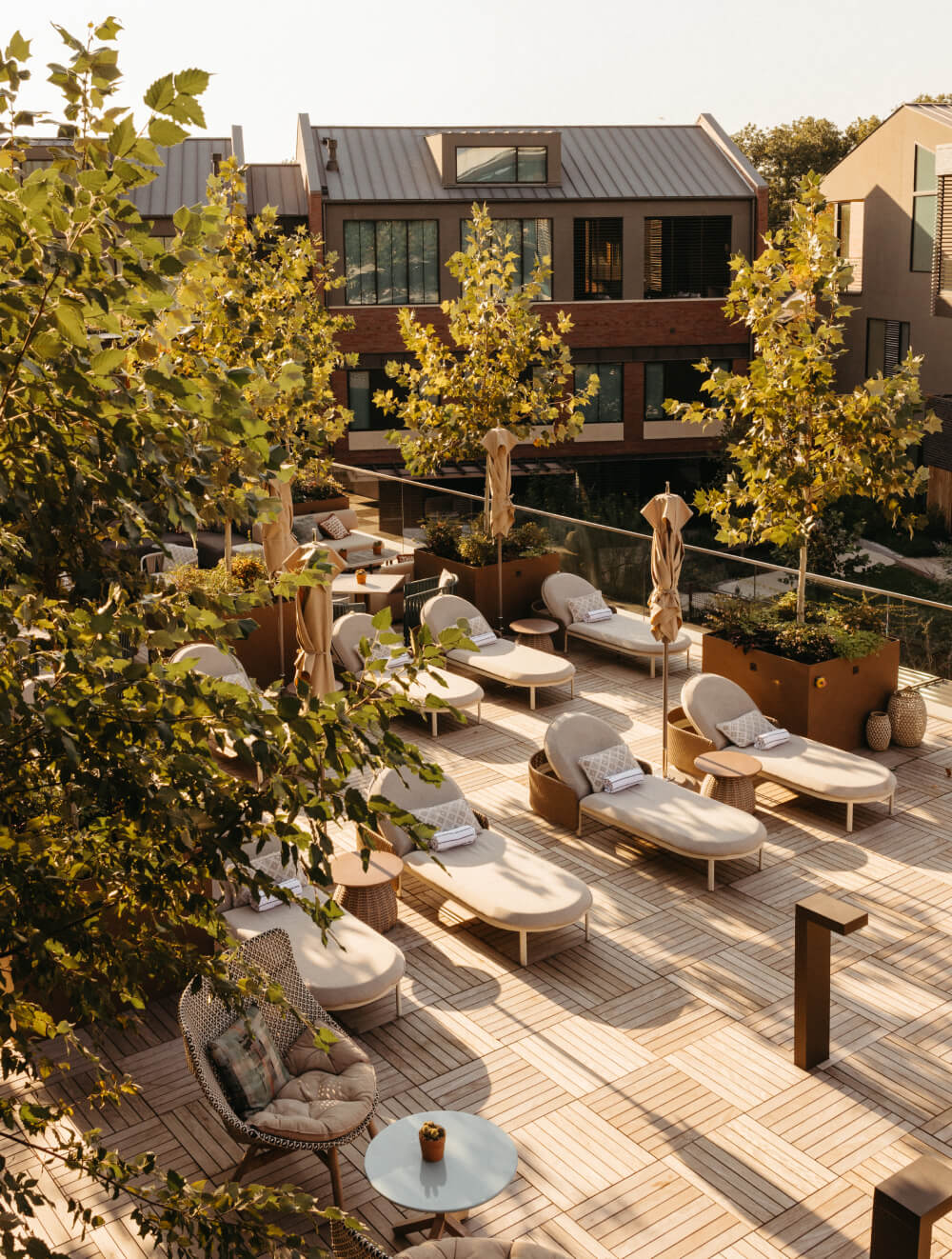 Exterior pool deck with upscale chaise loungers and umbrellas next to the pool.
